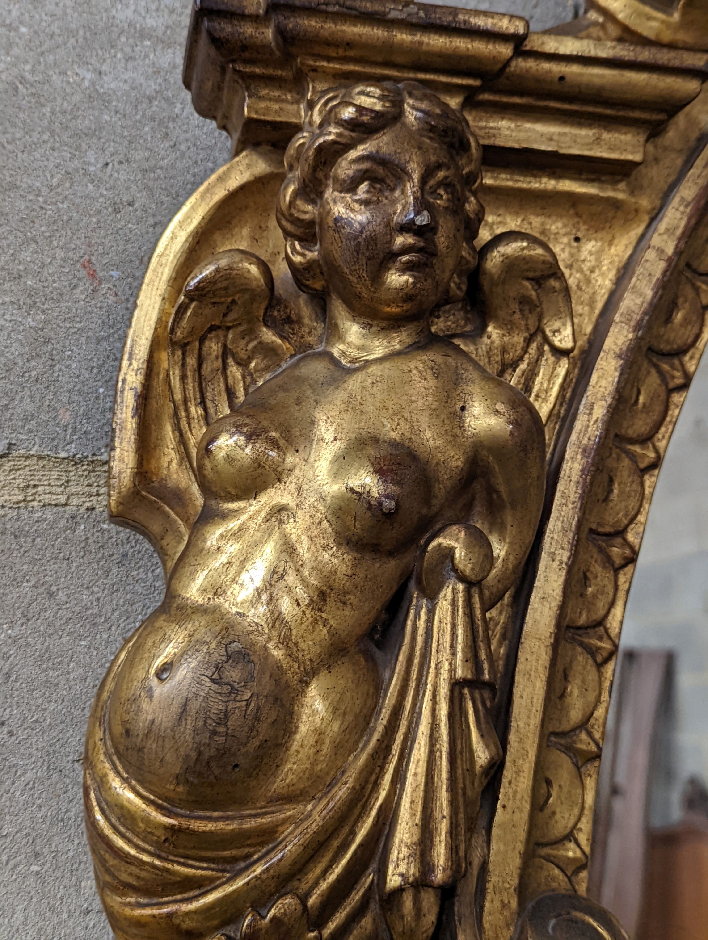 A Victorian carved giltwood oval wall mirror decorated with cherubs and C scrolls., width 74cm, height 110cm